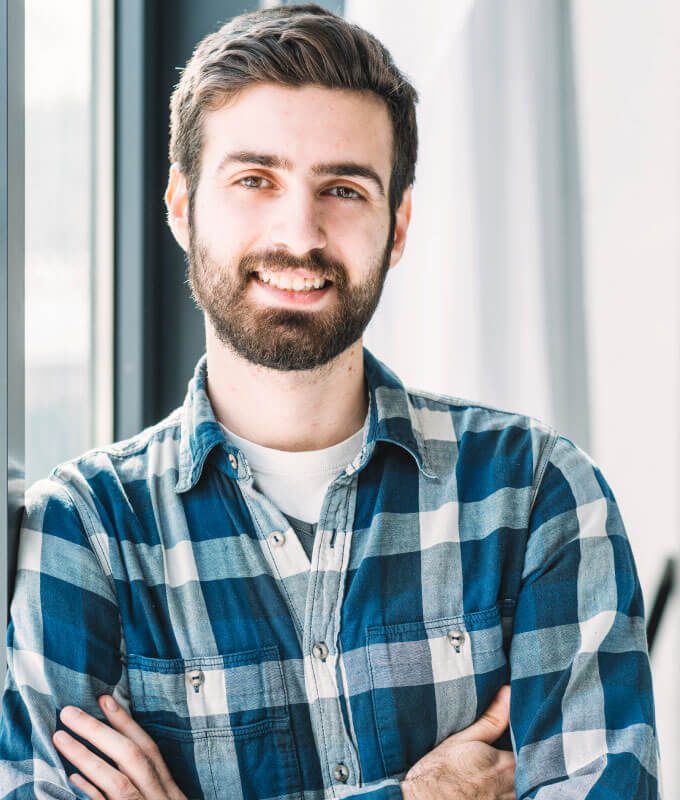 A man with beard and blue shirt smiling for the camera.