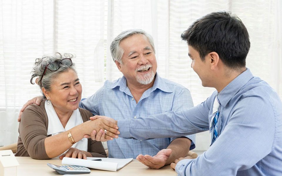 A man and woman shaking hands with an older couple.