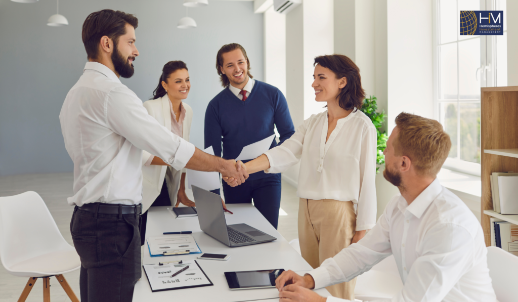 Business professionals shake hands at meeting.