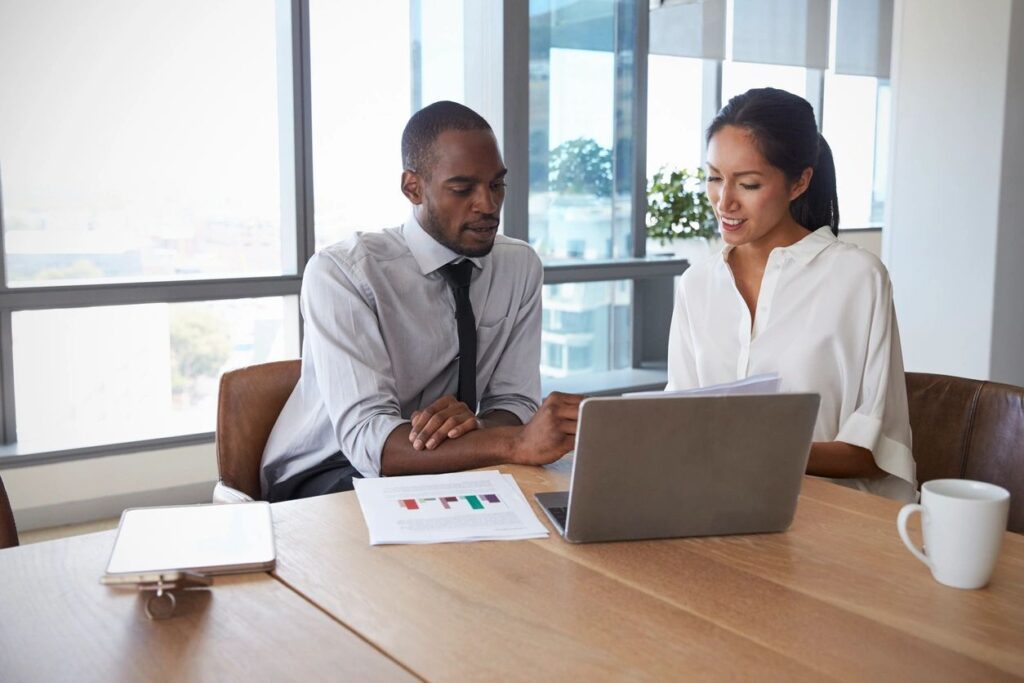 Two businesspeople reviewing documents at a desk.